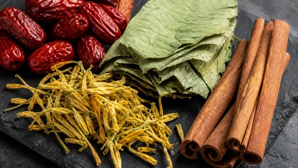 A detailed close-up shot of dried red dates, green lotus leaves, golden honeysuckle, and textured cinnamon bark A detailed close-up shot of dried red dates, green lotus leaves, golden honeysuckle, and textured cinnamon bark